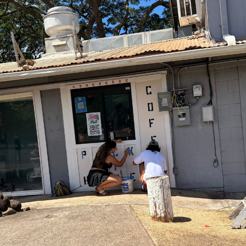 A new storefront with small business owners painting the signs